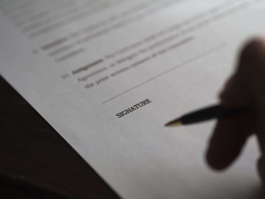Hand signing a contract with a personal injury lawyer after an accident