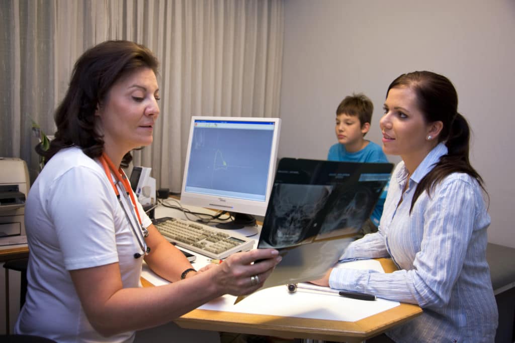 A doctor reviews x-ray scans with a car accident injury victim