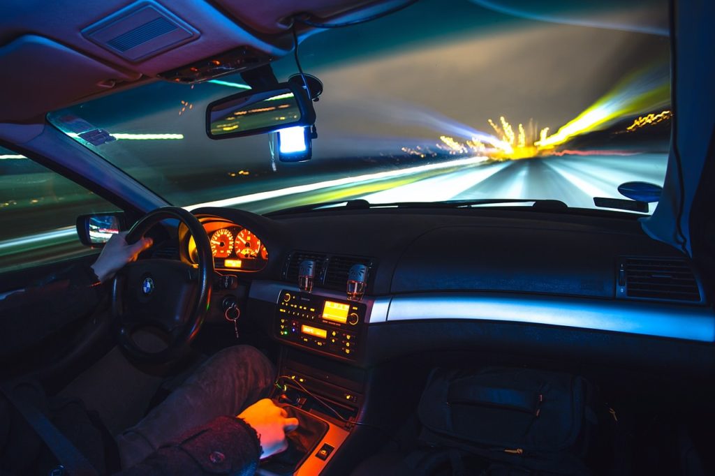View from the passenger side of a car of a driver on the freeway at night