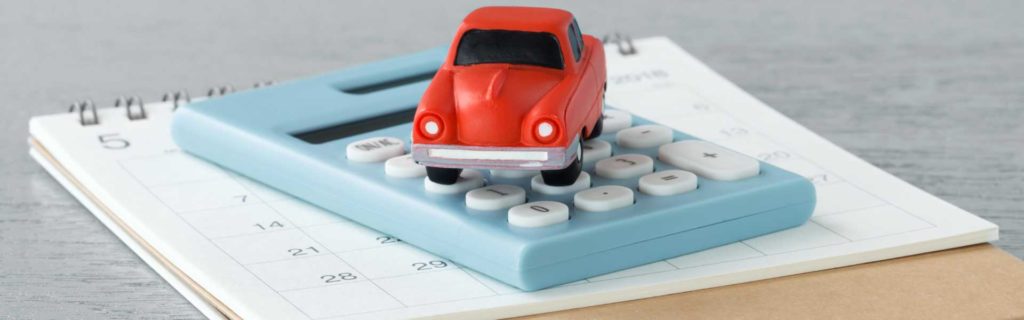 A toy car on top of a calculator representing car insurance payments
