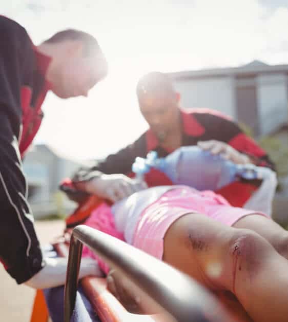 A paramedic gives oxygen to a woman with injuries from a car accident
