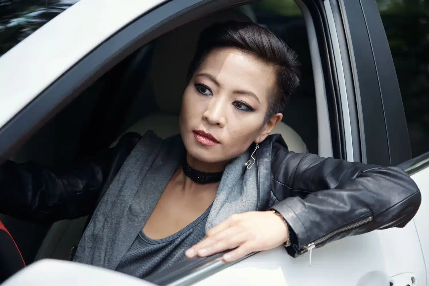 Woman leaning out of a car window while sitting in the driver's seat.