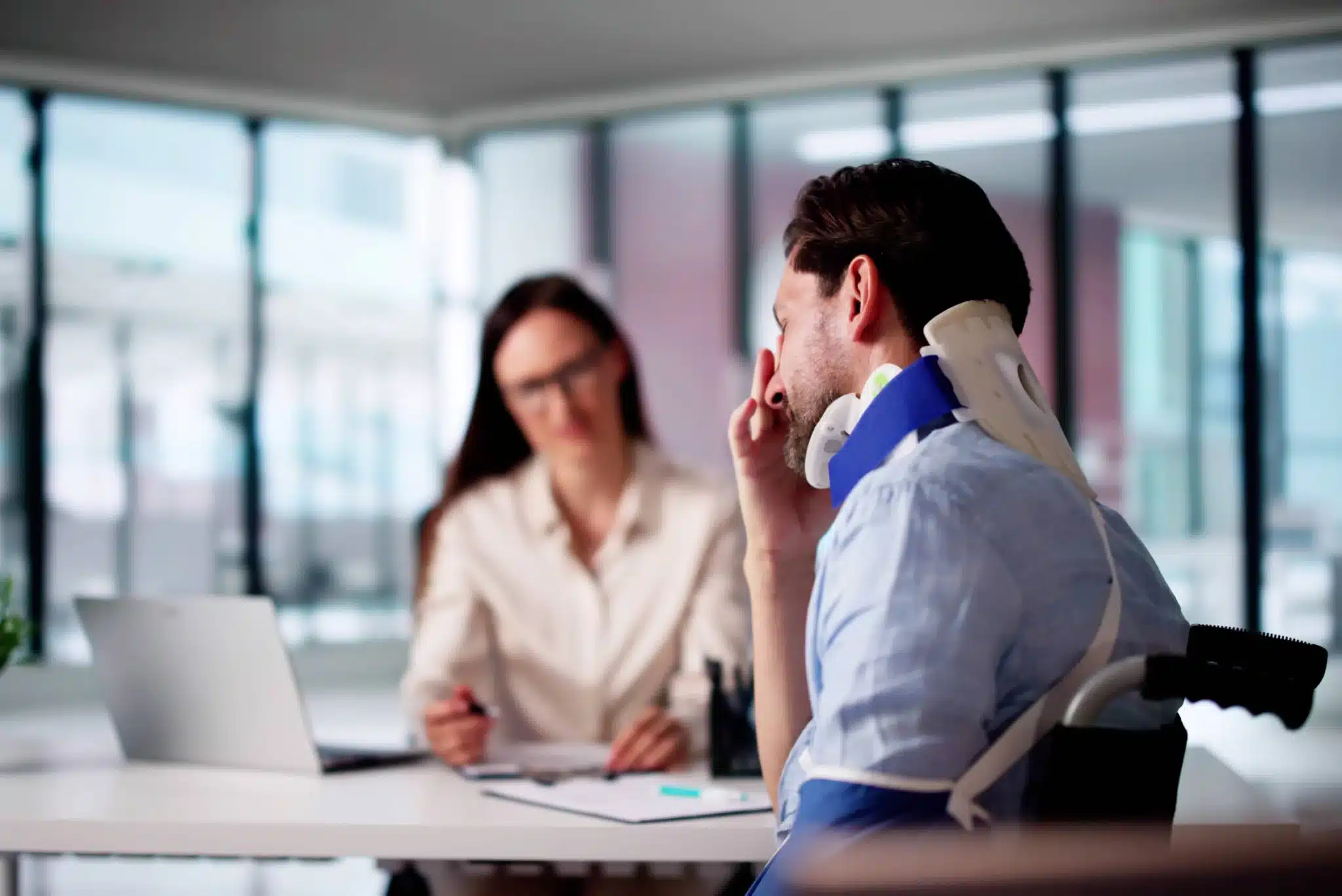 Injured man wearing a neck brace speaking with a lawyer during a consultation.