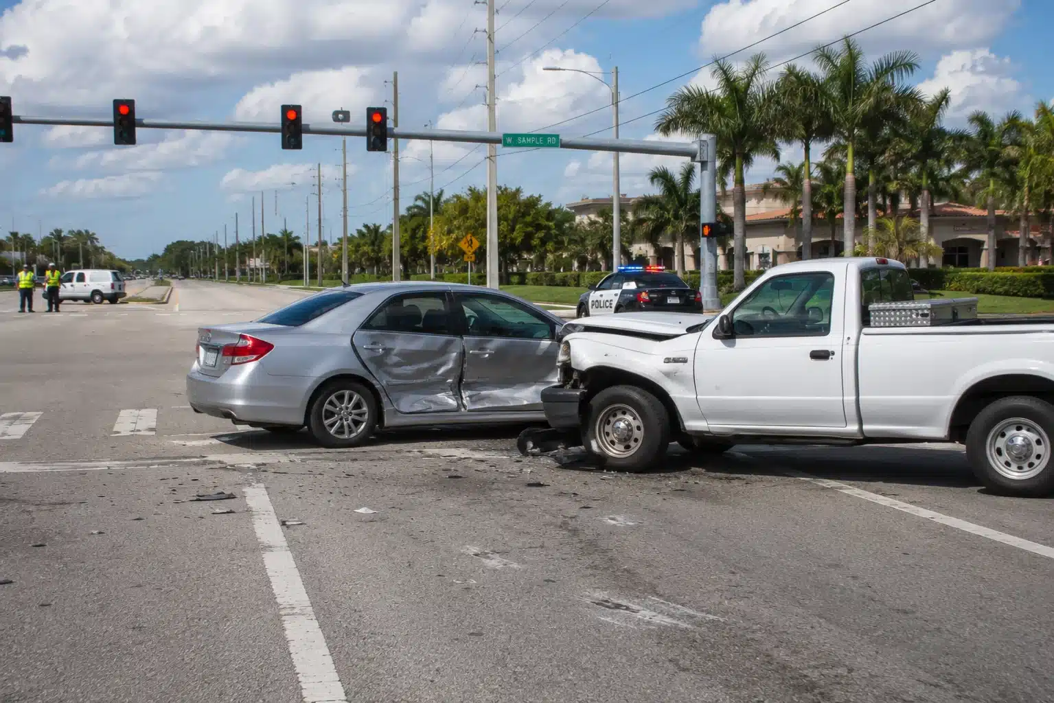 Colisión lateral entre un sedán plateado y una camioneta blanca en una intersección, con la policía en el lugar